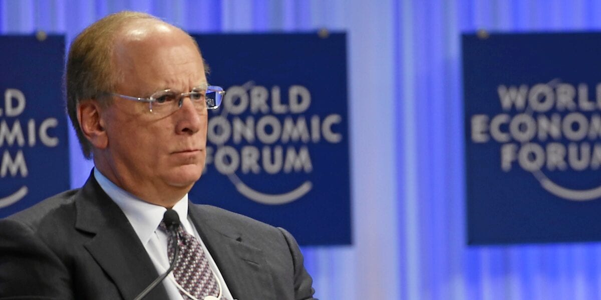BlackRock о будущем токенизированных ценных бумаг Мужчина в тёмном костюме и очках сидит на сцене на фоне логотипов Всемирного экономического форума